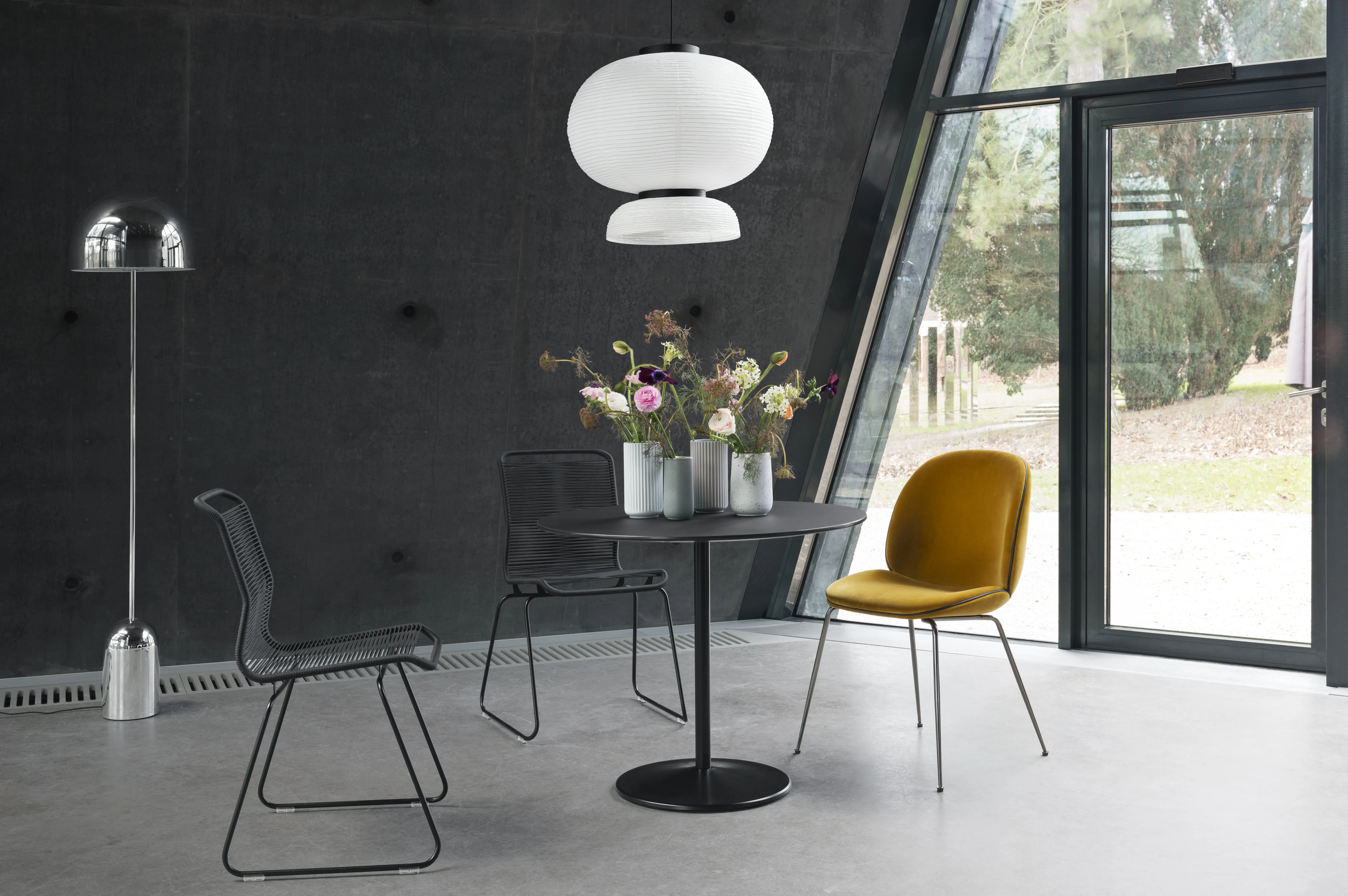 Panton One dining chairs woven in black & black cord surrounding a stainless steel table.